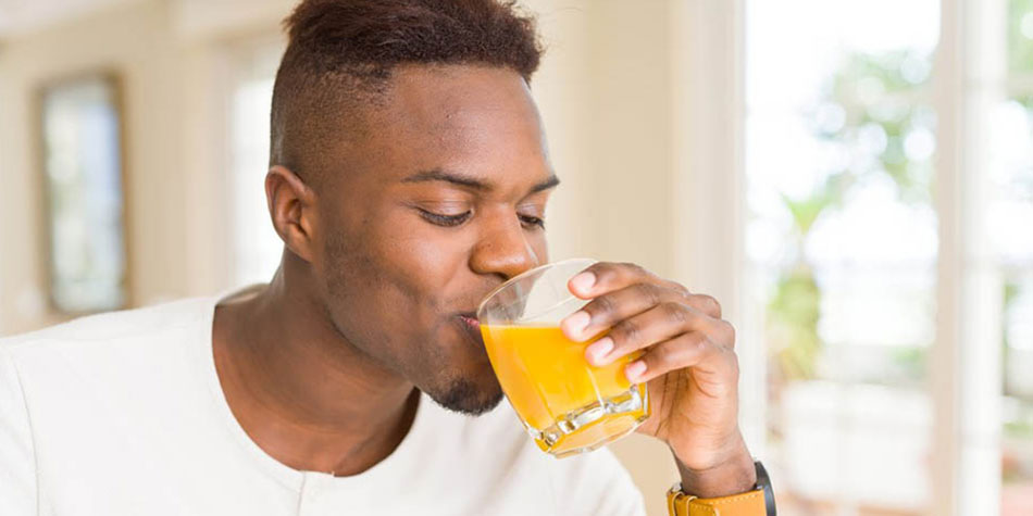 African American man drinking a glass of orange juice.