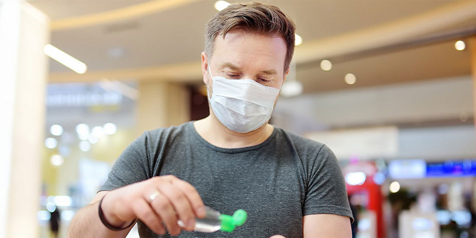 Man holding hand sanitizer wearing a mask.